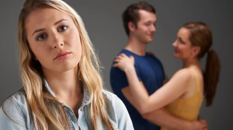 Một người ngồi lặng thinh giữa hai người đang thân mật