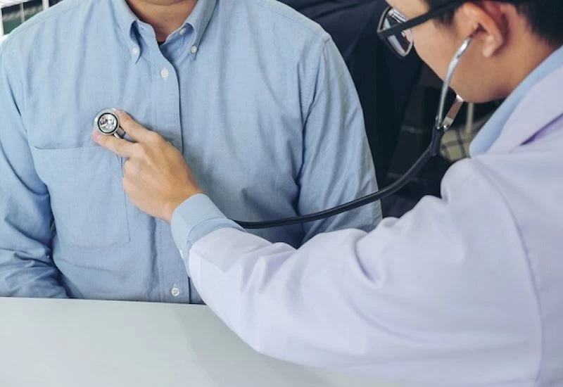 Bác sĩ kiểm tra tim cho nam giới trung niên tại phòng khám